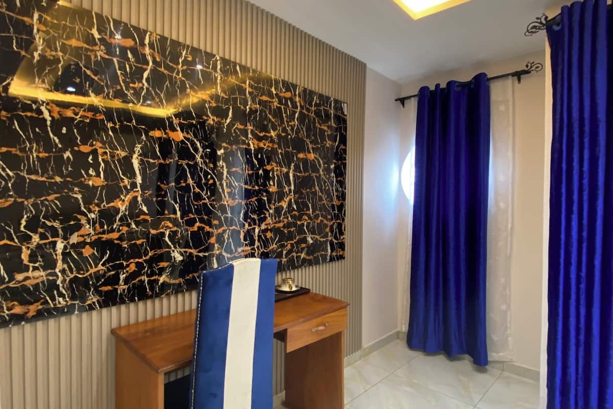 A modern room with a marble wall, a wooden desk, and blue curtains.