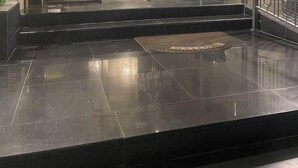 L’entrée d’un hôtel, avec une porte en verre, un comptoir d’accueil et un escalier menant à l’intérieur.