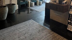 Una hall moderna con reception, area salotto e orologi a parete che mostrano diverse città.