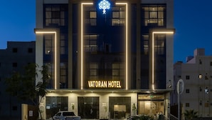 Un moderno edificio di hotel con una segnaletica ben visibile in arabo e inglese, che include un logo con un motivo a forma di cervello.