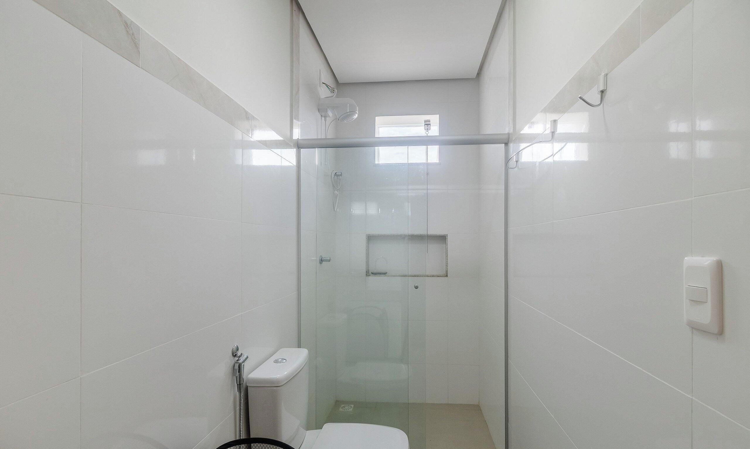 A small, enclosed shower area with a glass door, a toilet, and a towel rack.