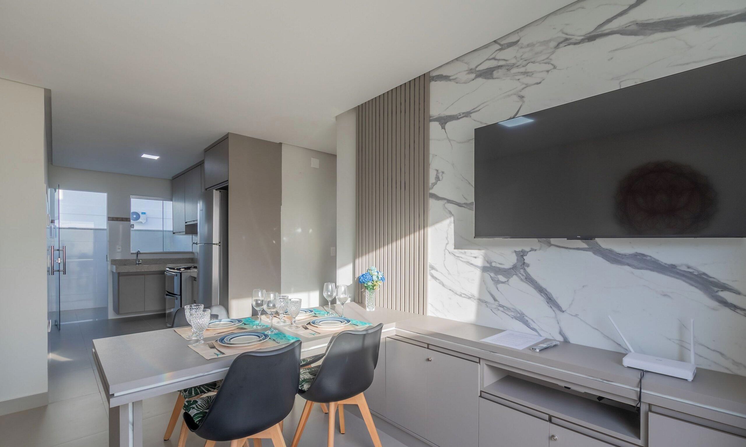 Een moderne keuken met een eethoek, een marmeren achterwand en een flatscreen-tv.