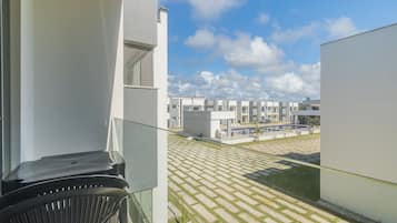 A modern building with a balcony overlooking a courtyard with patterned paving and a pool.