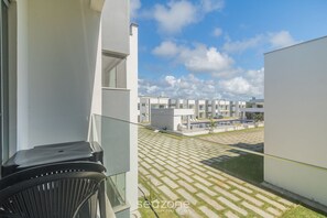 Un edificio moderno con un balcone che si affaccia su un cortile con pavimentazione decorata e una piscina.