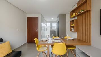 A modern dining area with a wooden table, yellow chairs, and a built-in shelf with decorative items.