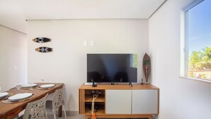 Un espace de vie moderne comprenant un téléviseur à écran plat fixé à un meuble en bois, une table à manger avec des chaises et un élément décoratif mural.