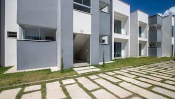 En modern byggnad med ett platt tak, stora fönster och en stenlagd innergård med gräs och stenplattor.