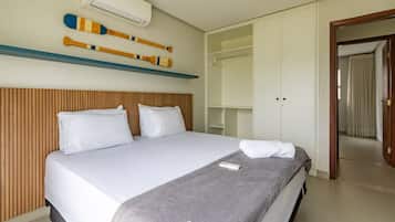 A hotel room with a bed, a wooden headboard, a wardrobe, and a mirror.