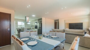 Un espace repas moderne avec une table rectangulaire dressée pour quatre personnes, entourée de chaises rembourrées.