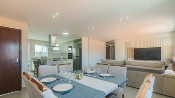 A modern dining area with a rectangular table set for four, surrounded by cushioned chairs.