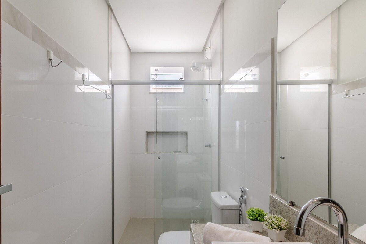 Un bagno moderno con cabina doccia in vetro, un WC, un lavabo con specchio e una piccola finestra per la luce naturale.