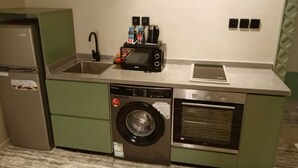 Een compacte kitchenette met een wasmachine, een magnetron, een broodrooster en een kleine oven.