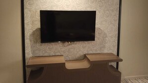 Een flatscreen-tv bevestigd aan een muur met behang met een patroon.