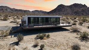 A modern, single-story building with a flat roof, large glass windows, and a flat roof deck. - Late for the Sky • Modern Marvel with Hot Tub (Joshua Tree)