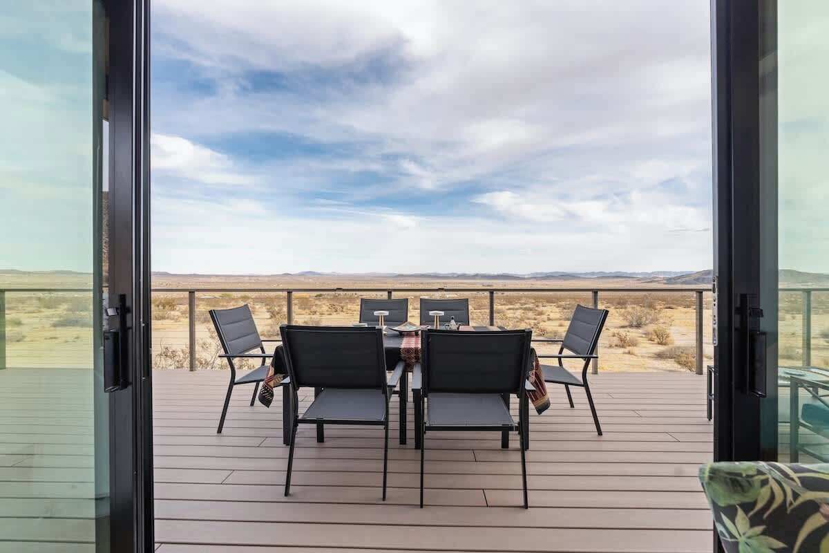 Een terras met een tafel en stoelen, met uitzicht op een woestijnlandschap.