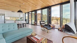 A spacious living area with a sofa, a fireplace, and a view of the outdoors. - Late for the Sky • Modern Marvel with Hot Tub (Joshua Tree)