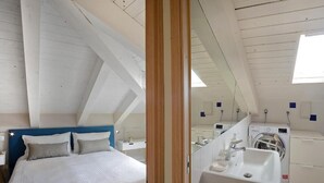 A bedroom with a bed, a bedside table, a mirror, and a washing machine in the adjacent room. - Willy's Home (Salerno)