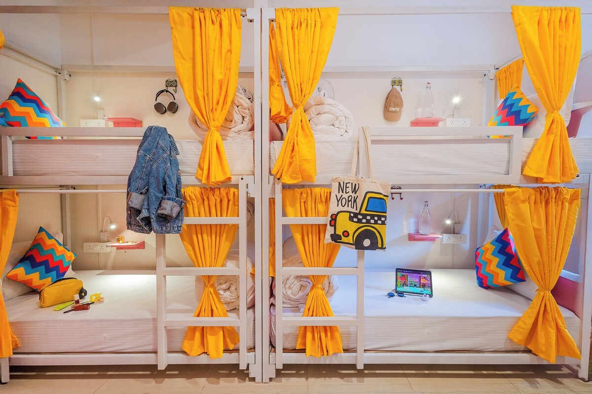 A bunk bed room with yellow curtains, a denim jacket, and a 'New York' sign.