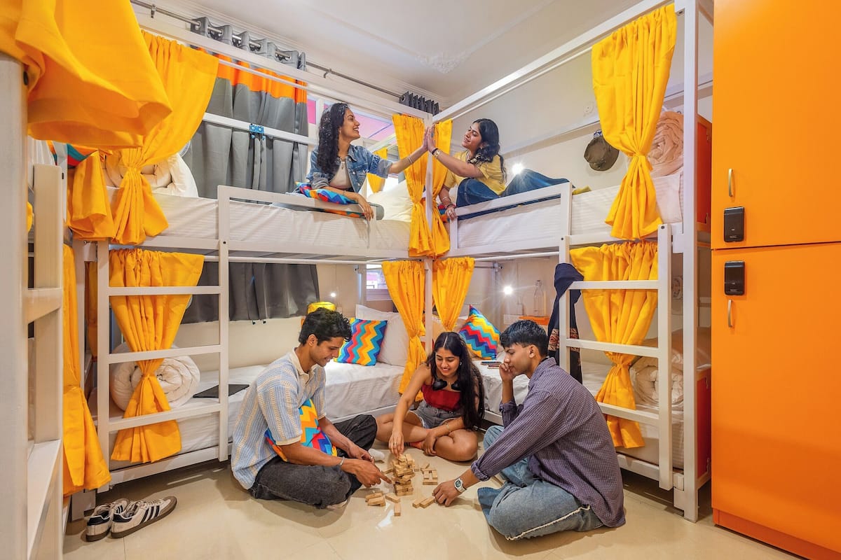 A bunk room with yellow curtains, a white wardrobe, and a bed with a pillow.