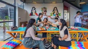 A 24/7 in-house cafe with colorful furniture and artwork on the walls. - goSTOPS Mcleodganj, Mall Road (McLeod Ganj)