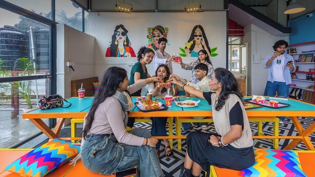 A 24/7 in-house cafe with colorful furniture and artwork on the walls. - goSTOPS Mcleodganj, Mall Road (McLeod Ganj)