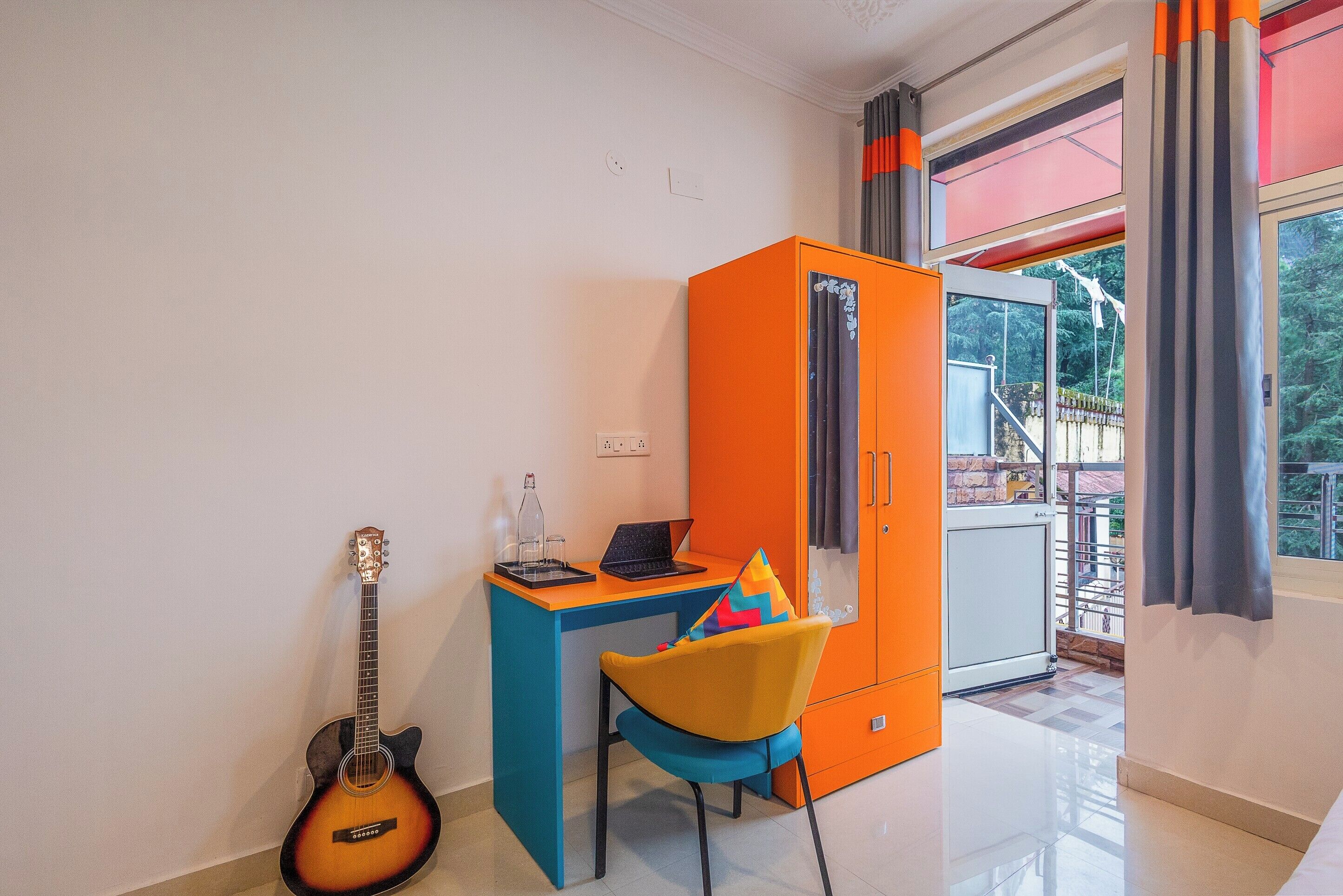 A room with a blue desk, a guitar, and an orange cabinet.