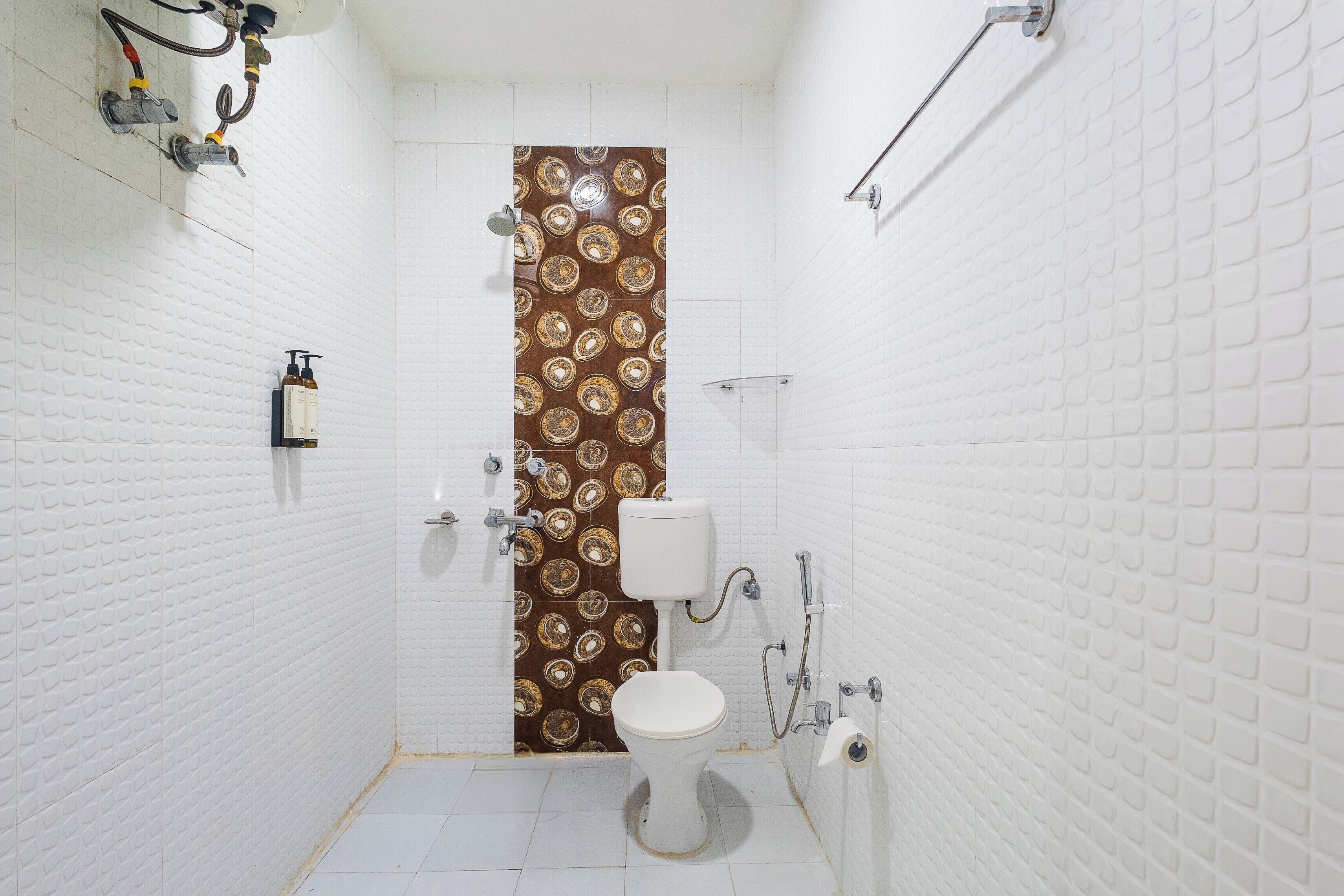 A small, white-walled bathroom with a patterned door, a toilet, and a shower.