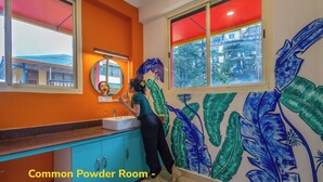A bathroom with a sink, mirror, and a wall with a leaf pattern. - goSTOPS Mcleodganj, Mall Road (McLeod Ganj)