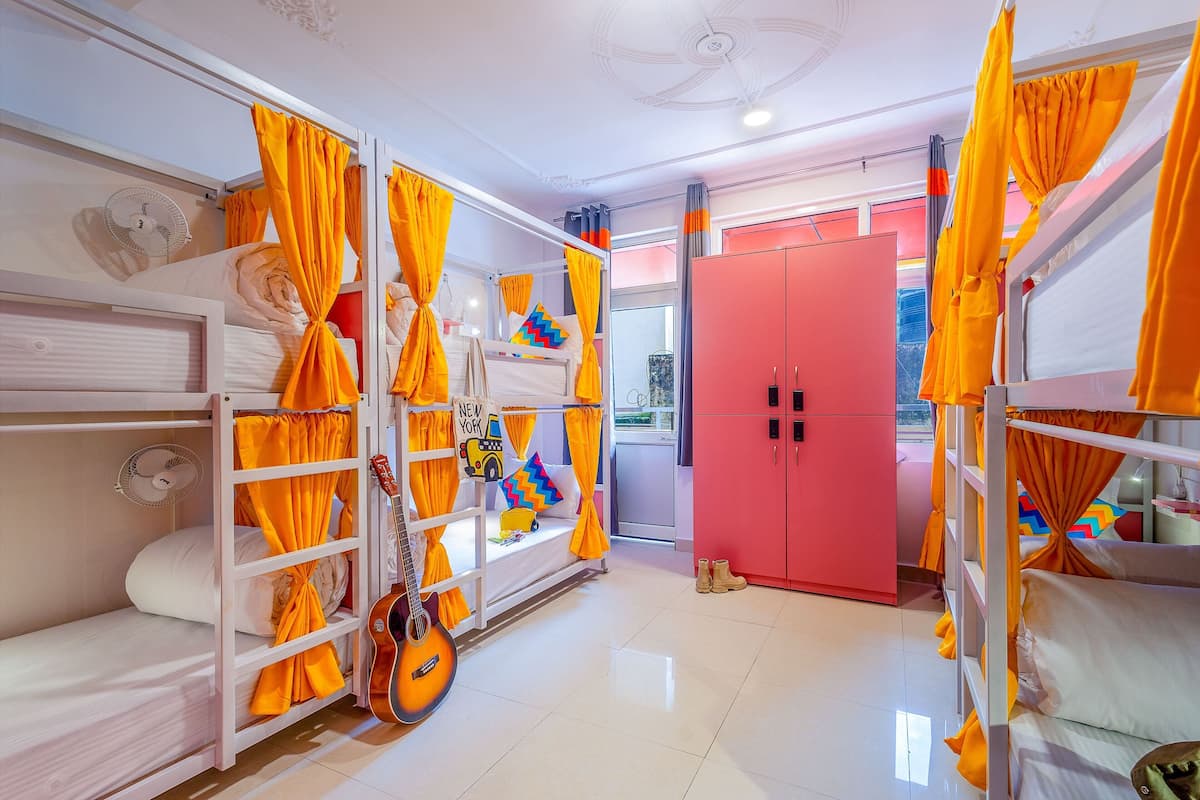 A room with bunk beds, a guitar, and a red wardrobe.