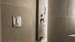 A bathroom with a toilet, a shower control panel, and a wall-mounted faucet. - Haza Manzeli Rabwa Branch (Madinah)