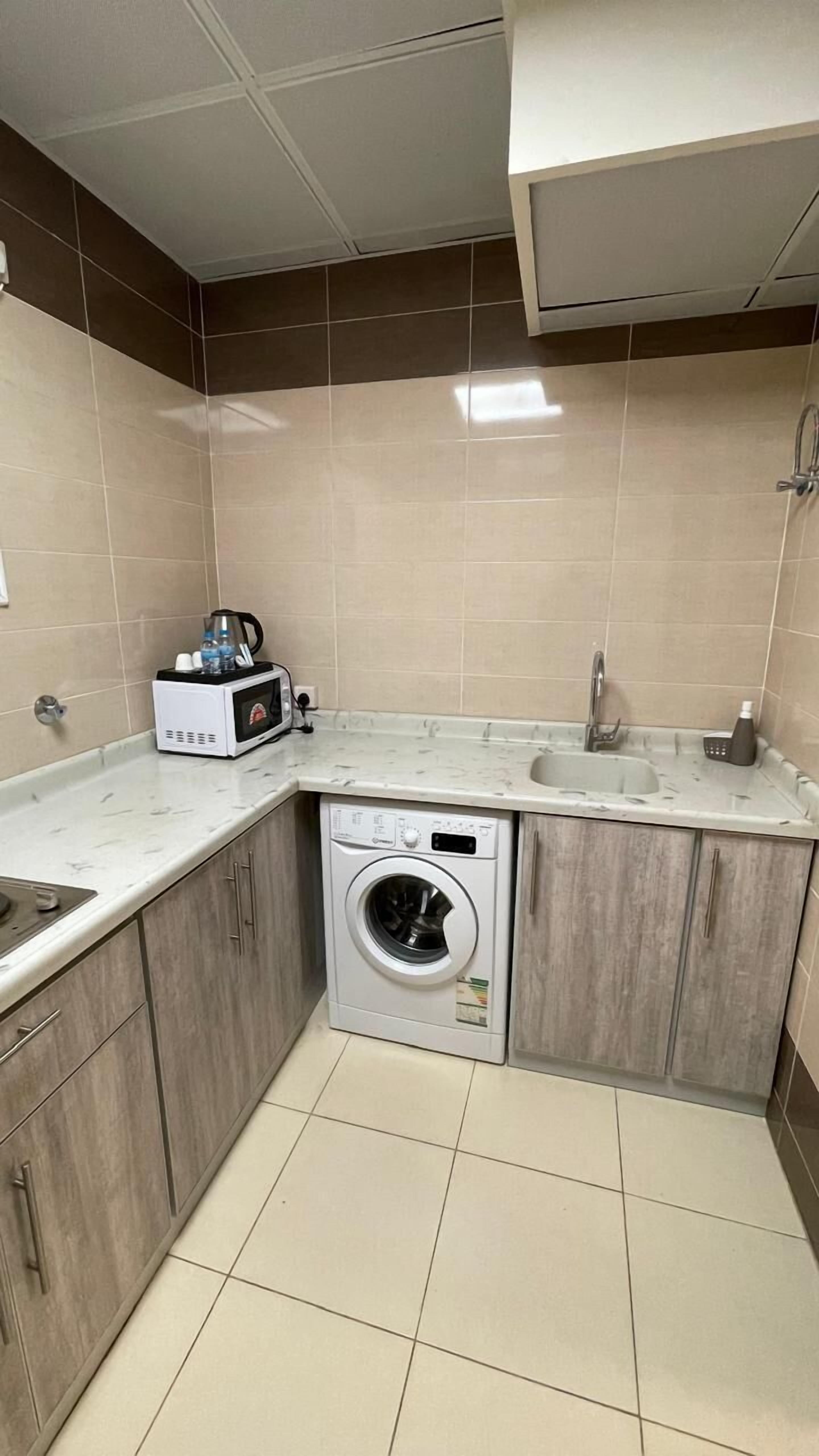 Una cocina compacta con lavadora integrada, un microondas y un lavabo.