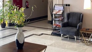 Un hall d’entrée spacieux au design moderne, comprenant un canapé gris, une table basse et un vase décoratif agrémenté de plantes.