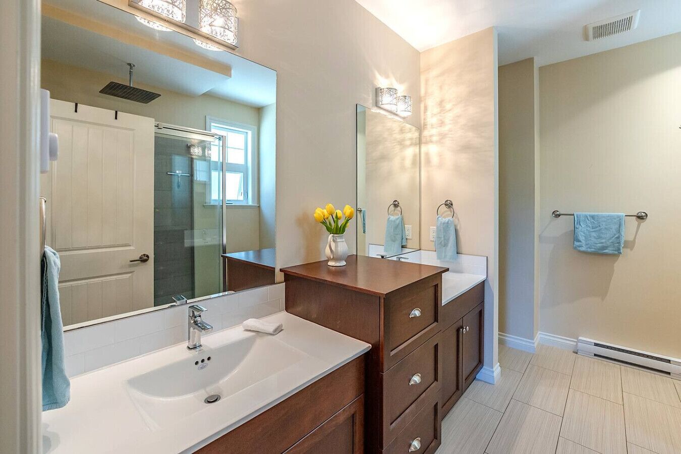 Een moderne badkamer met twee wasbakken, een spiegel en een douche.