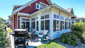 Ein Haus mit überdachter Terrasse, Essbereich mit Gartenmöbeln und Garage.