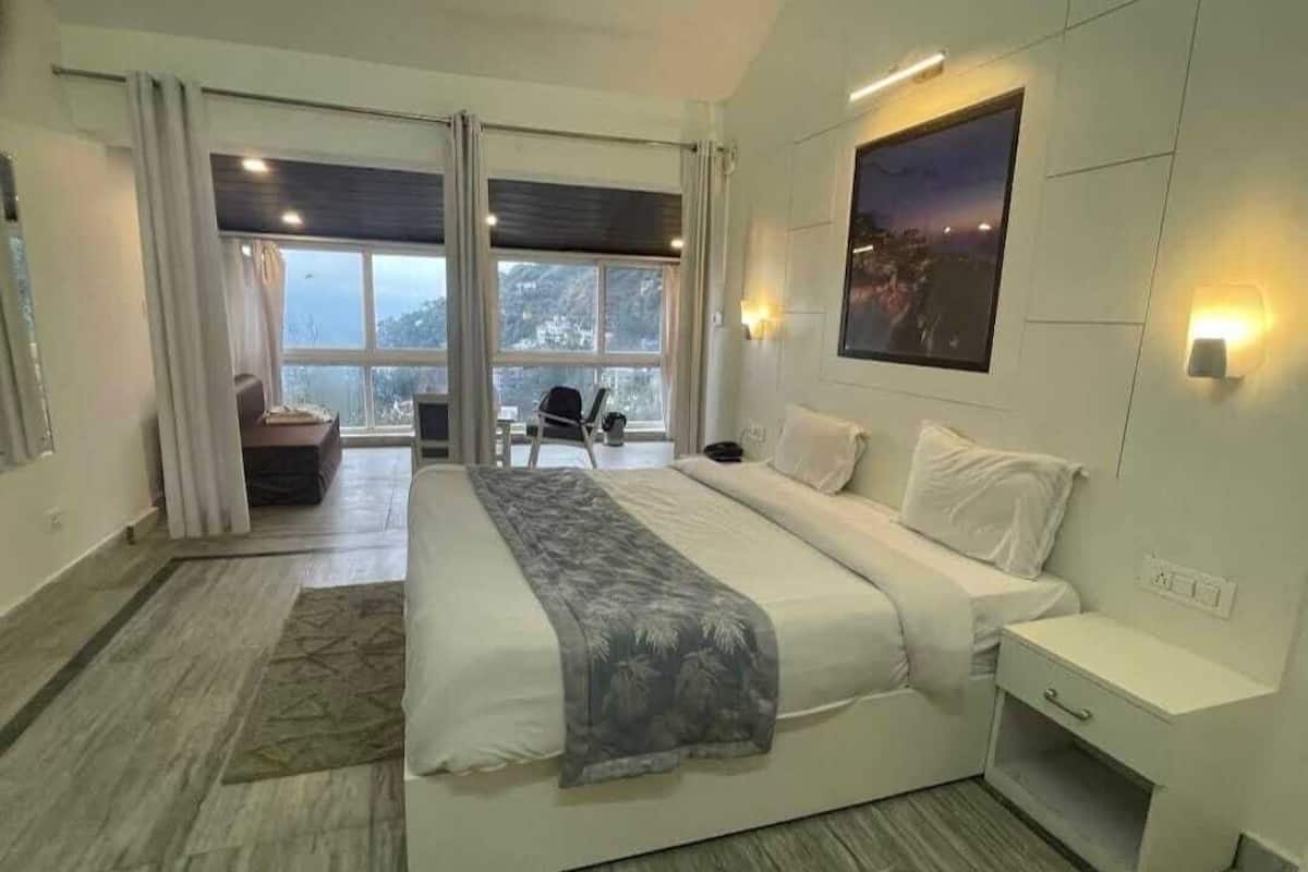 A modern hotel room with a large bed, a desk, and a view of the outdoors.