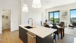 A modern kitchen with a central island, pendant lighting, and a dining area with a view.