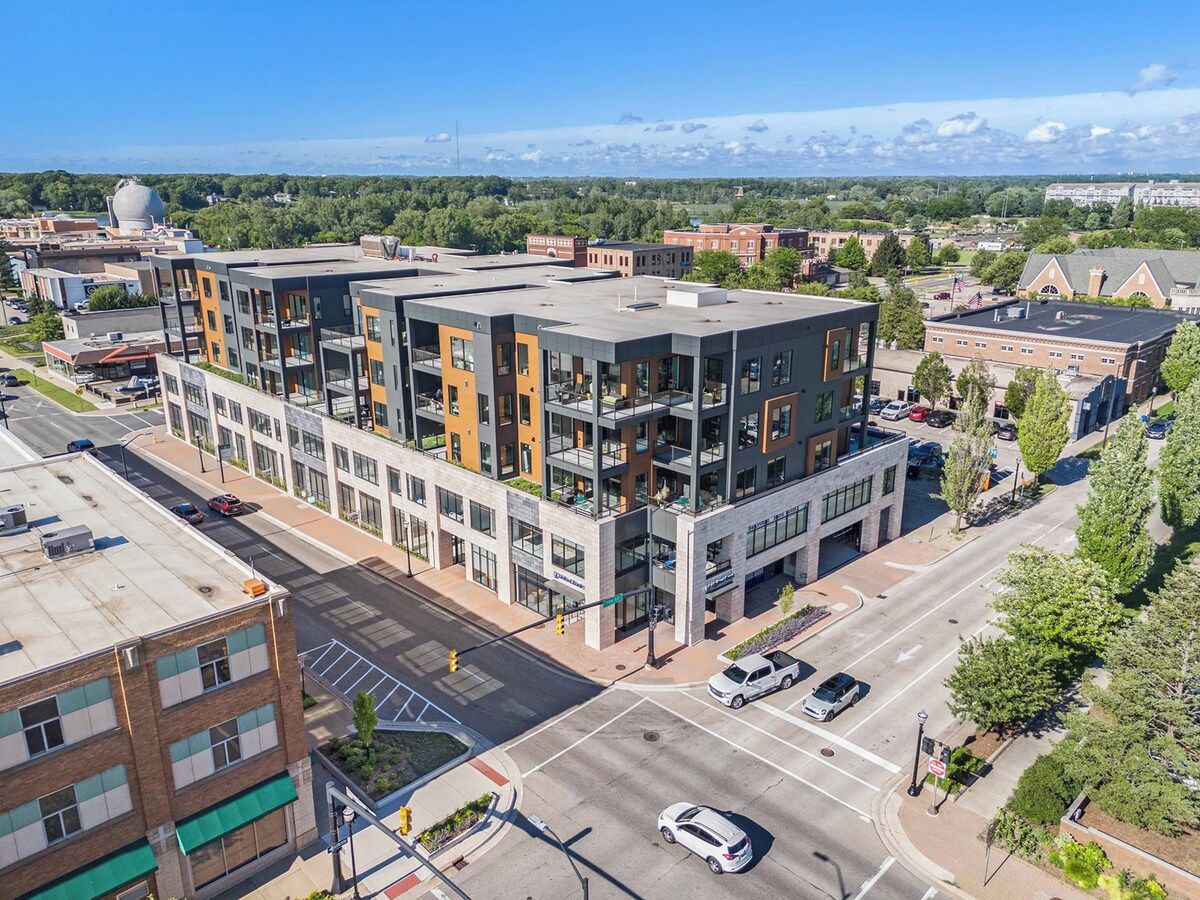A multi-story building with a flat roof, large windows, and a parking lot.