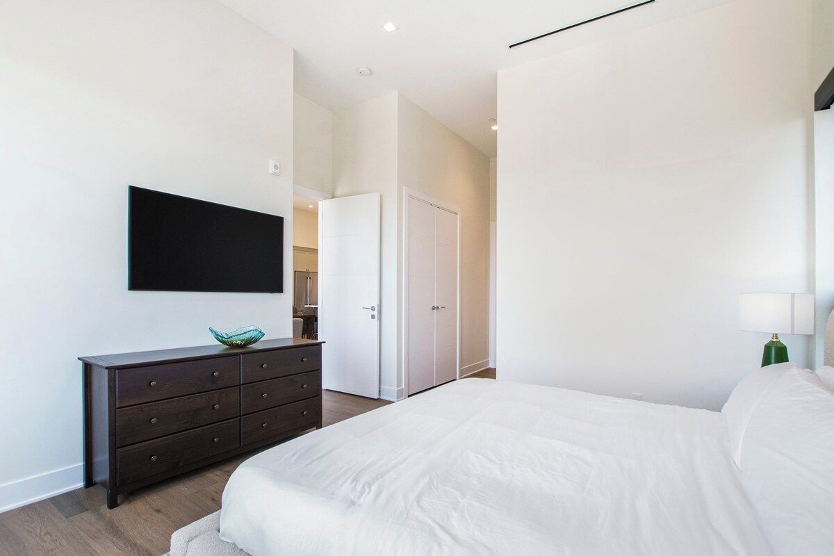 A bedroom with a bed, a dresser, a television, and a wardrobe.