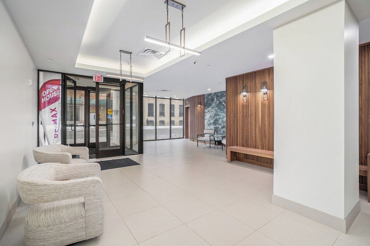 A modern hotel lobby with a glass door entrance, seating area, and wooden paneling.