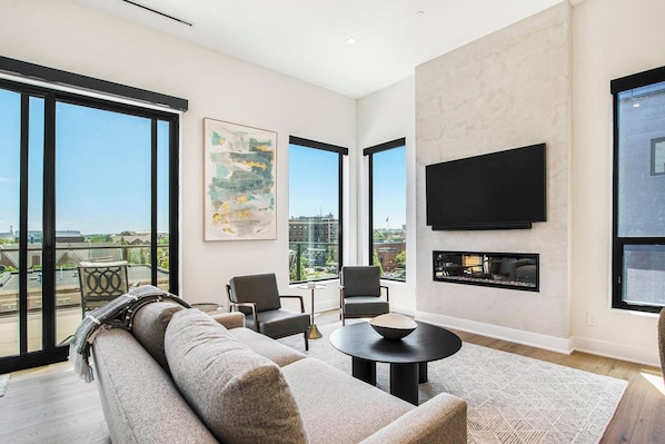 A modern living room with a sofa, chairs, a coffee table, and a fireplace.