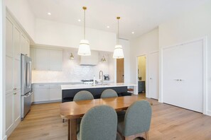 Et moderne køkken med en central ø, rustfrie stålapparater og hængende lamper.