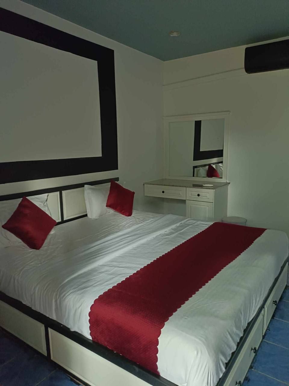 A hotel room with a bed, a bedside table, a mirror, and a wardrobe.