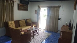 Una sala de estar con un sofá, sillones, una mesa de centro y un televisor.