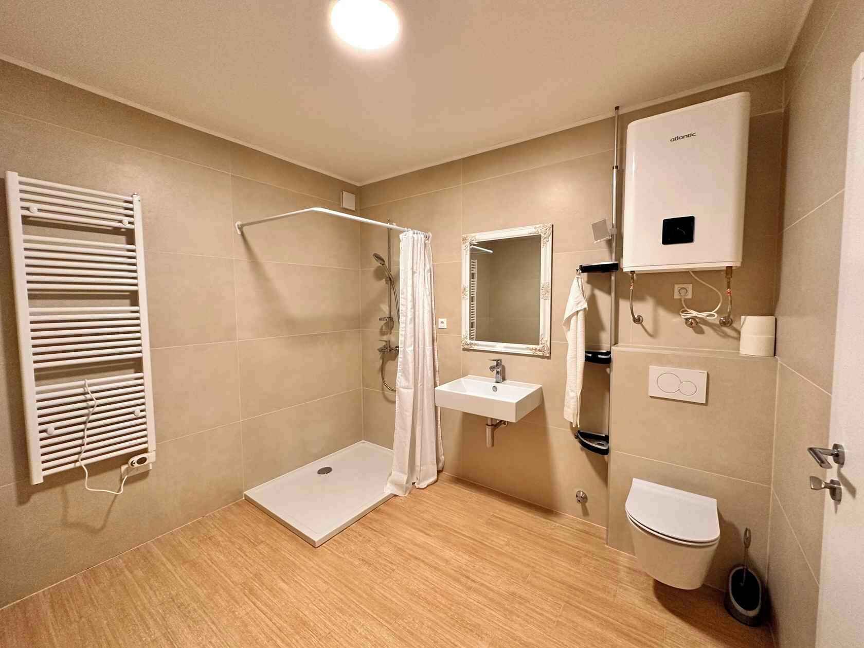 Un baño moderno con ducha, lavabo, inodoro y perchero para toallas.