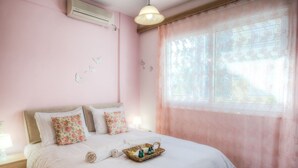 Une chambre à coucher comprenant un lit, une table de chevet, une lampe, une fenêtre avec des rideaux et des éléments de décoration murale.