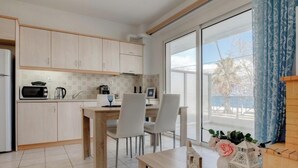 Une cuisine moderne avec des meubles en bois clair, une table à manger avec des chaises et une grande fenêtre donnant sur l’extérieur.