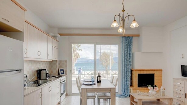 Une cuisine moderne avec un coin repas, une cheminée et une vue sur la mer.