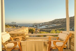 En terrasse med træstole og udsigt over en kystby.
