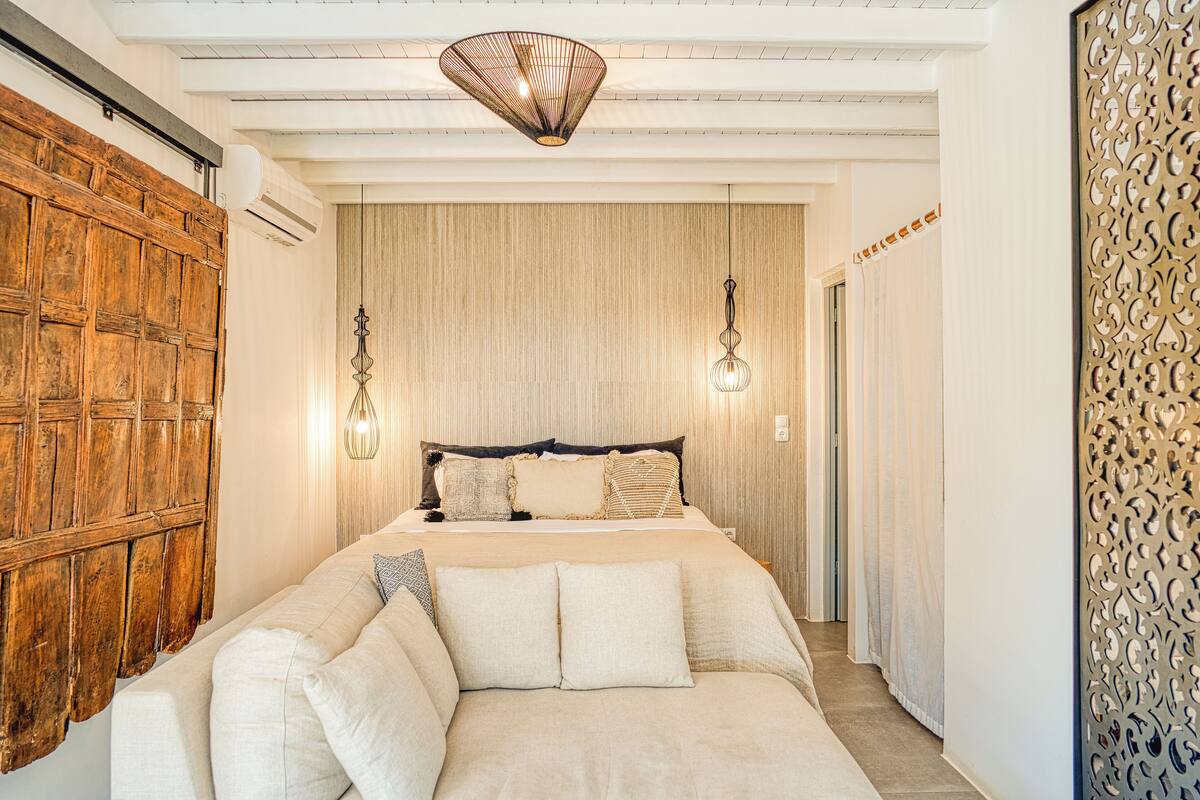 A bedroom with a large bed, a wooden wardrobe, and a decorative wall panel.
