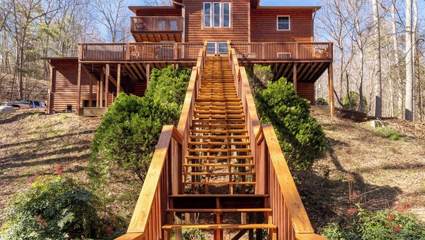 A two-story wooden cabin with a central staircase leading to a balcony.